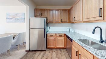 A kitchen with wooden cabinets and a stainless steel refrigerator. at Hillsborough Apartments, Roseville, Minnesota
