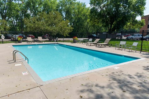 a swimming pool with lounge chairs and trees in the background