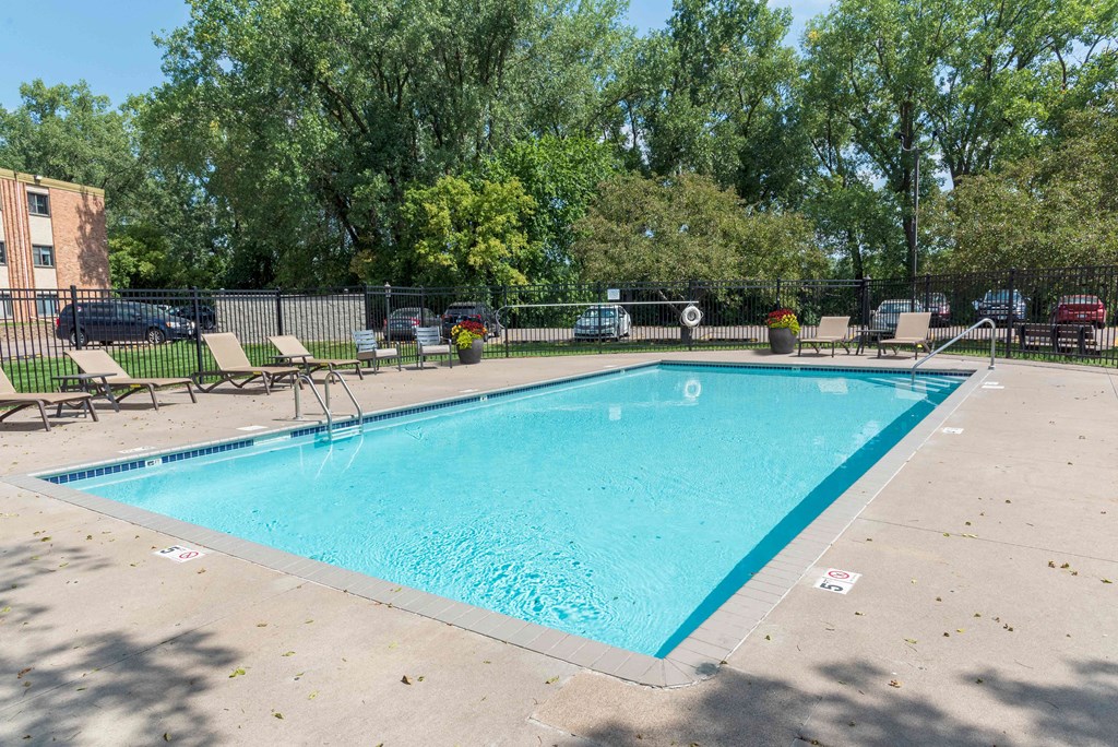 a swimming pool with chaise lounge chairs and trees in the background