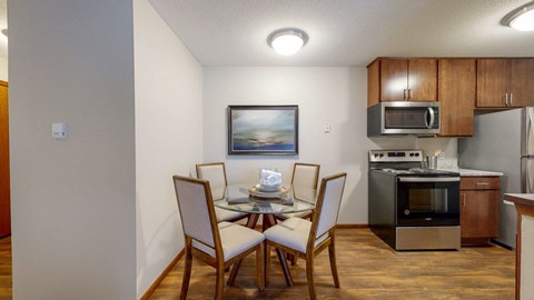 a dining area with a table and chairs and a kitchen in the background