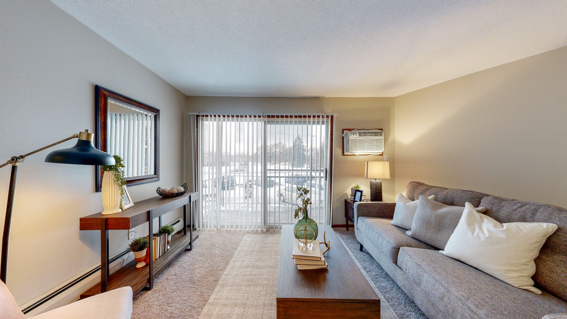 a living room with a gray couch and a sliding glass door