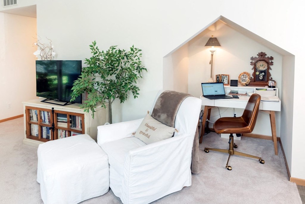 a living room with a white couch and a desk with a computer