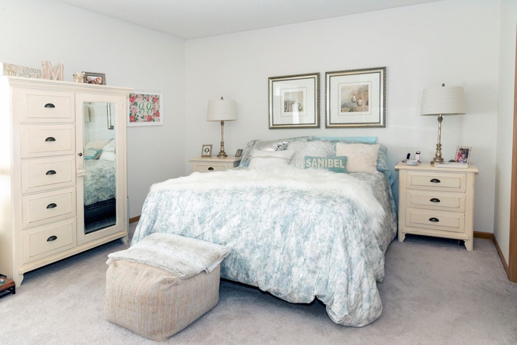 a bedroom with white walls and a bed with a white comforter and blue pillows
