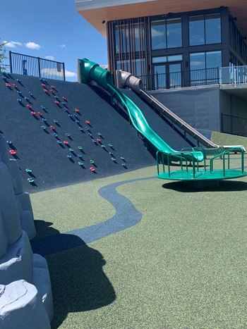 a green slide on the side of a building with a blue sky in the background