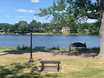 a picnic area with a bench next to a lamp post and a lake in the background
