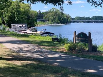 a path along the water with boats in the background