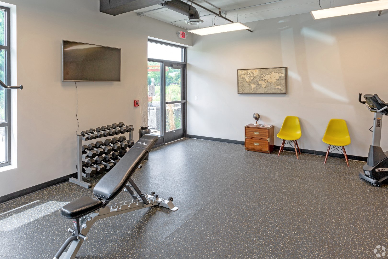 a gym with a exercise bike in the middle of the room and a television on