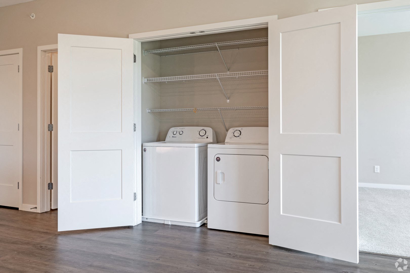 an open closet with washer and dryer in a room with a wood floor
