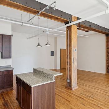 A kitchen with a granite countertop and wooden floors.