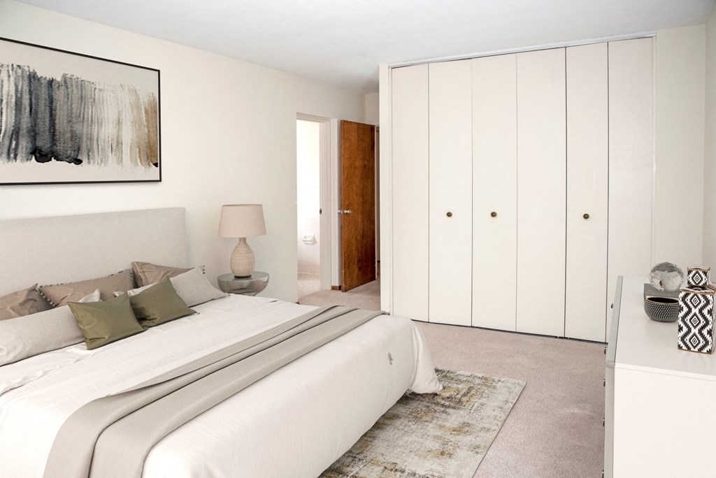 a white bedroom with a large bed and white closets