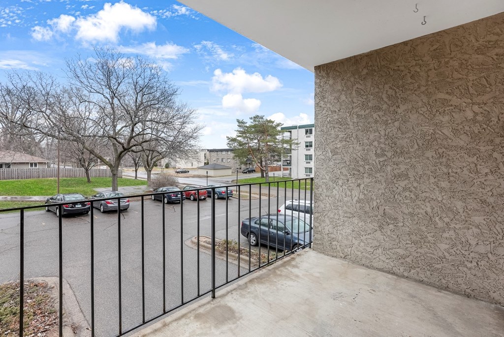 the view of a parking lot from a balcony with a metal gate