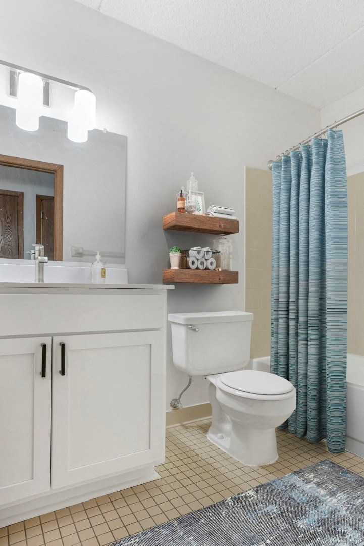 a bathroom with a white toilet and a blue shower curtain