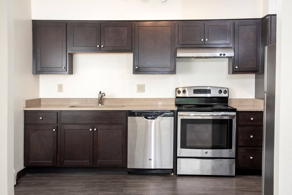 a kitchen with dark wood cabinets and stainless steel appliances