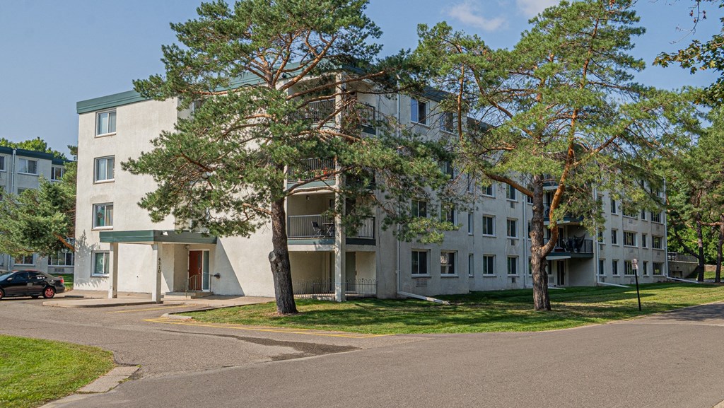 a large white apartment building with trees in front of it