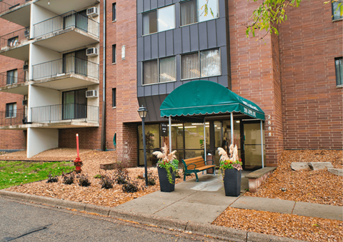 A building with a green awning and potted plants in front.