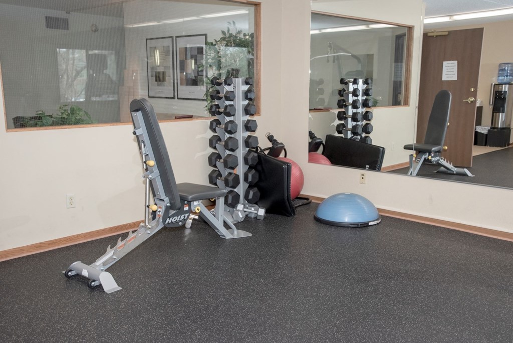 a gym with weights on the floor and a mirror