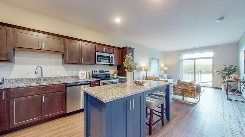 a kitchen with a large island and a living room in the background
