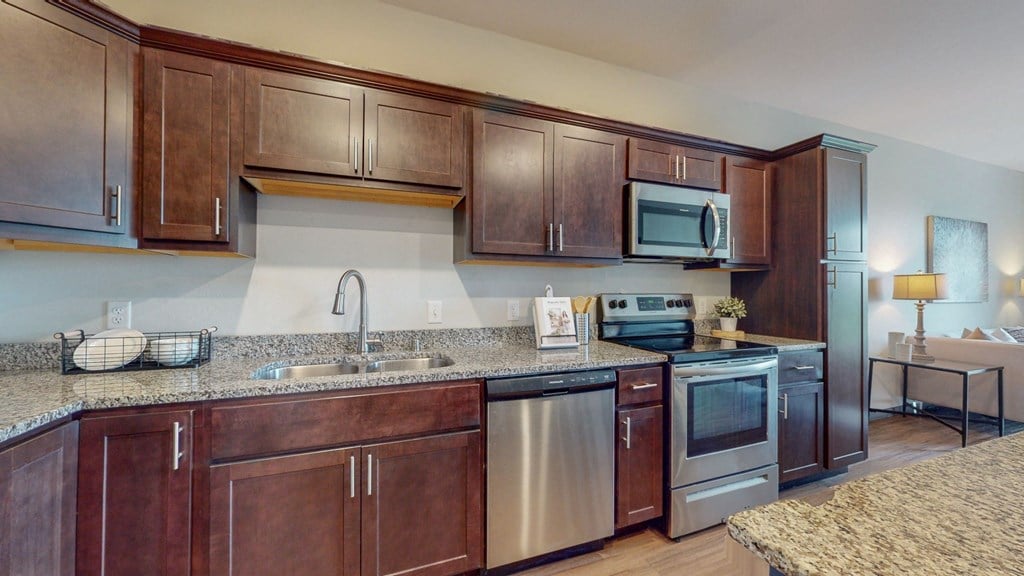 a kitchen with dark wood cabinets and granite countertops at Lake Jonathan Flats, Chaska, MN