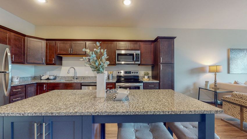 a kitchen with a large island and a living room in the background