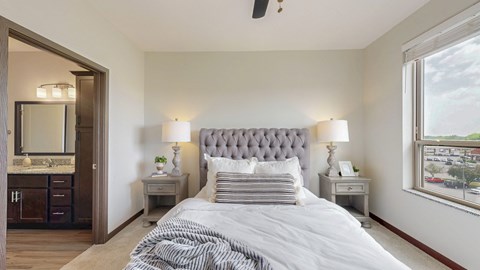 A bedroom with a large bed and a window overlooking a cityscape.