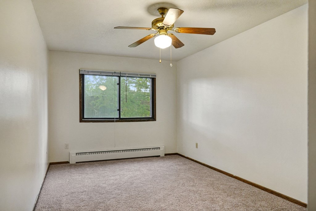 an empty living room with a ceiling fan and a window