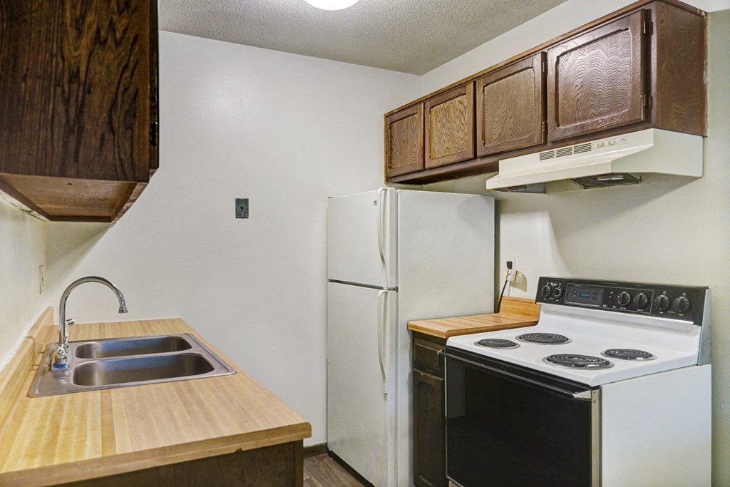 an empty kitchen with a stove refrigerator and sink