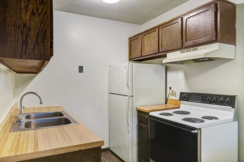 an empty kitchen with a stove refrigerator and sink