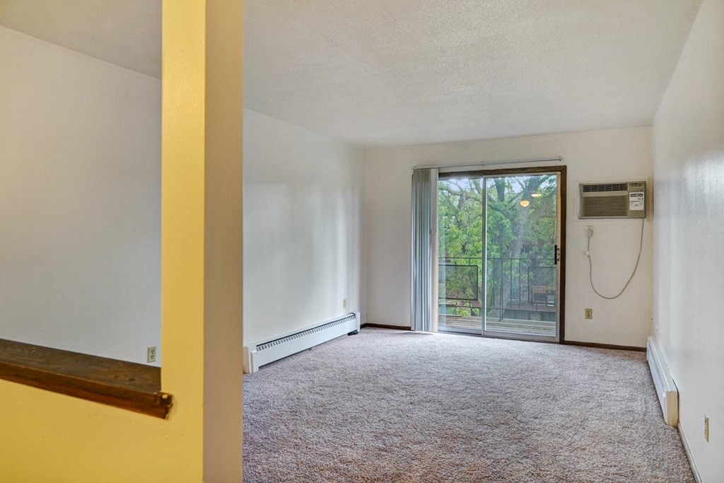 an empty living room with a sliding glass door to a patio