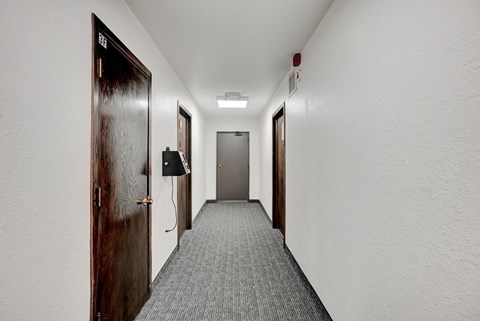 a long hallway with doors and white walls and a carpeted floor