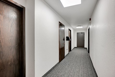 a long corridor with doors and white walls and a carpeted floor