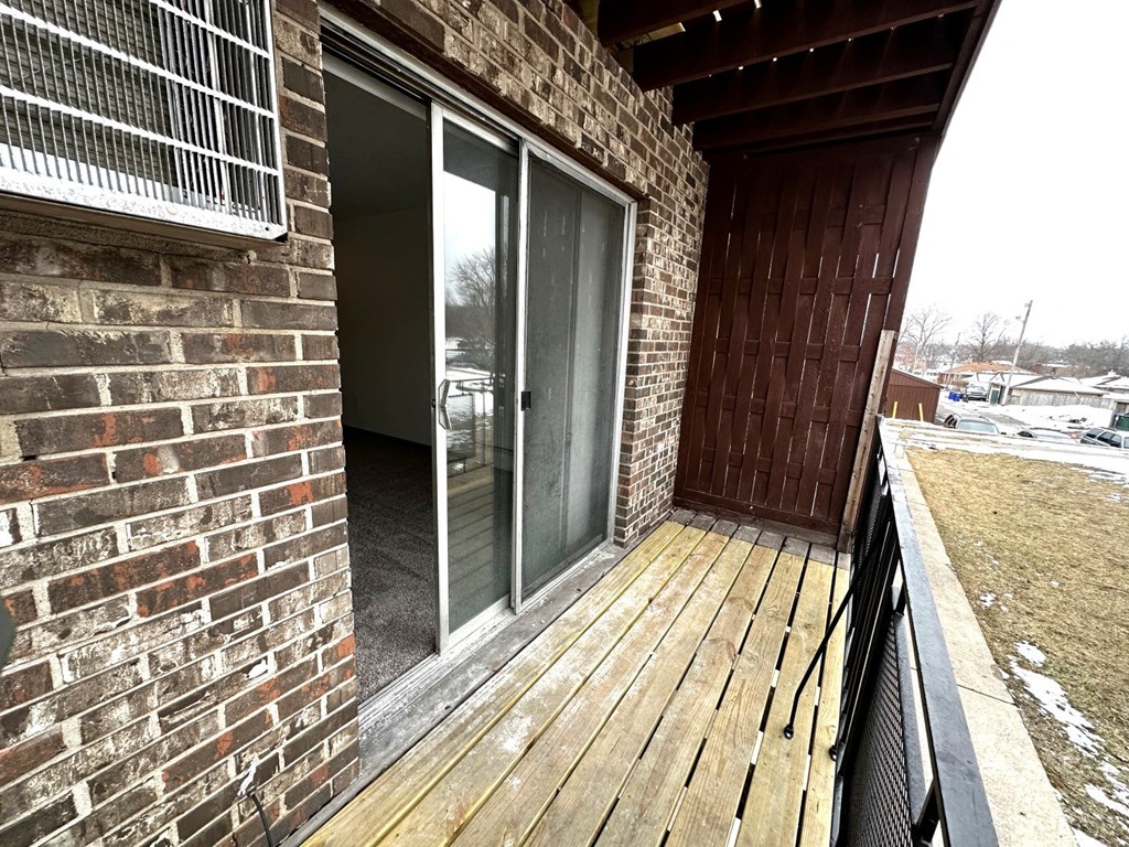 a balcony with a wooden deck and a brick wall