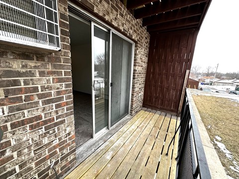 a balcony with a wooden deck and a brick wall