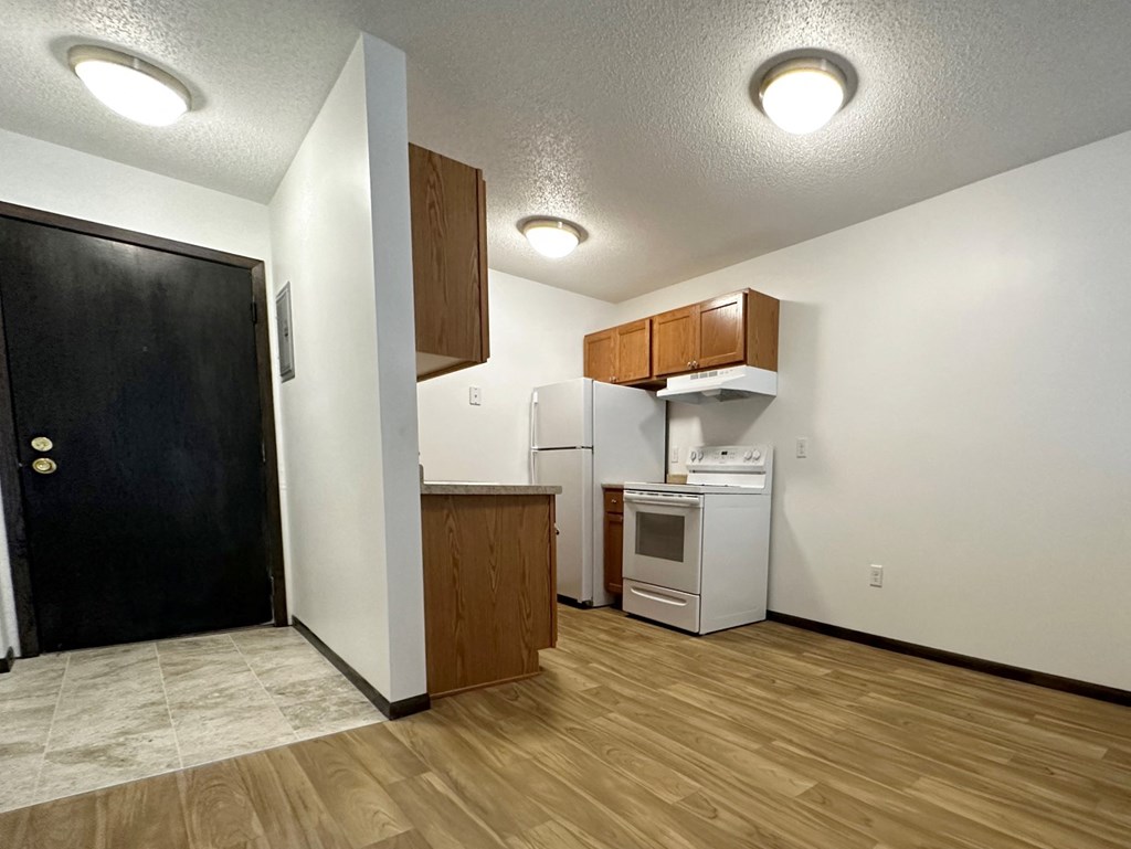 an empty kitchen with a refrigerator and a stove and a door
