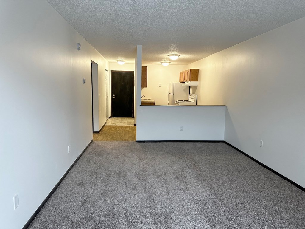 the living room and kitchen of an empty apartment