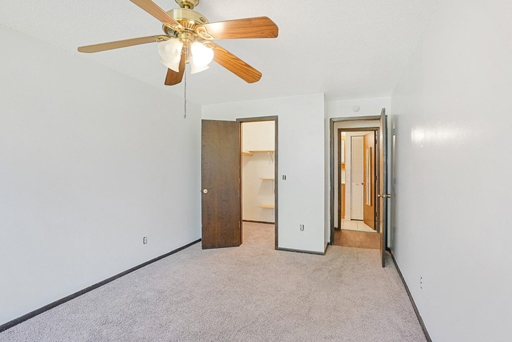 a bedroom with a ceiling fan and a door to a bathroom