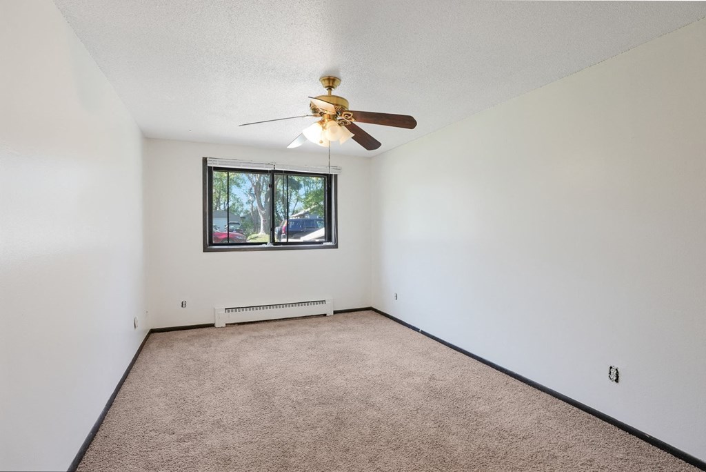 an empty living room with a ceiling fan and a window