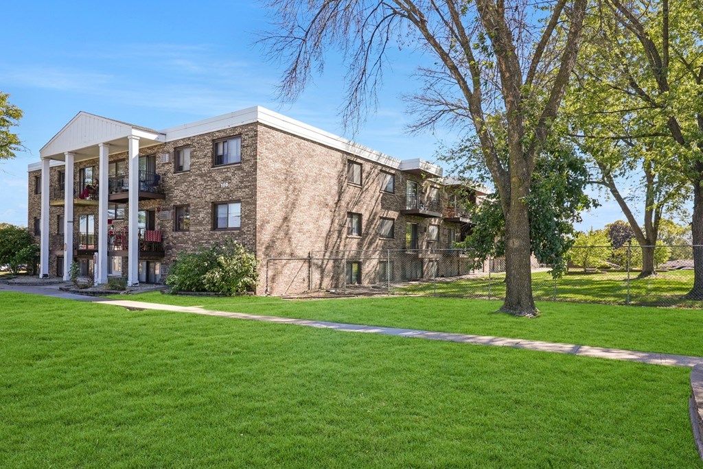 a building with a green lawn and trees in front of it