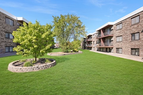 a green lawn in front of a building with trees