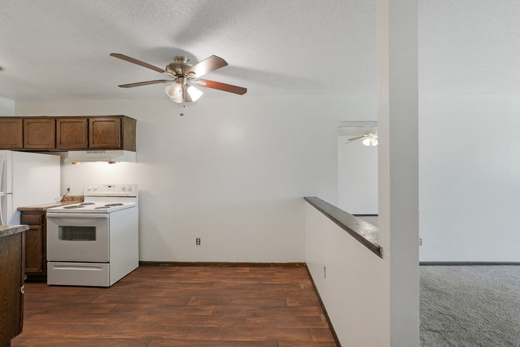 an empty kitchen with a ceiling fan and white appliances