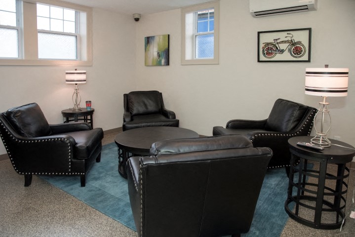 a living room with black leather furniture and a blue rug