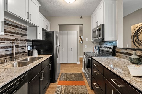 A kitchen with black and white cabinets and a granite counter top.