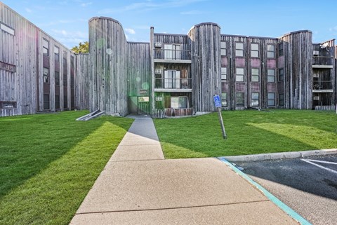 the exterior of an apartment building with grass and a sidewalk