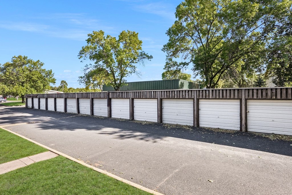 a row of white garage doors and a fence on a street