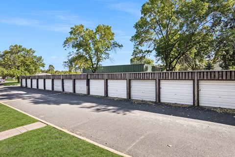a row of white garage doors and a fence on a street