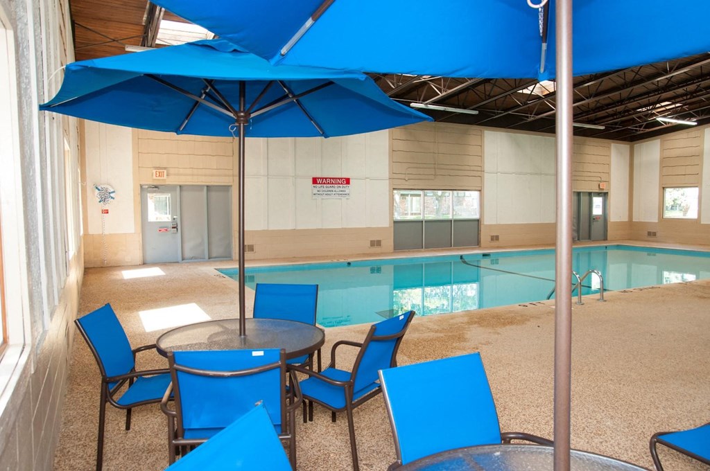 a large swimming pool with blue chairs and umbrellas