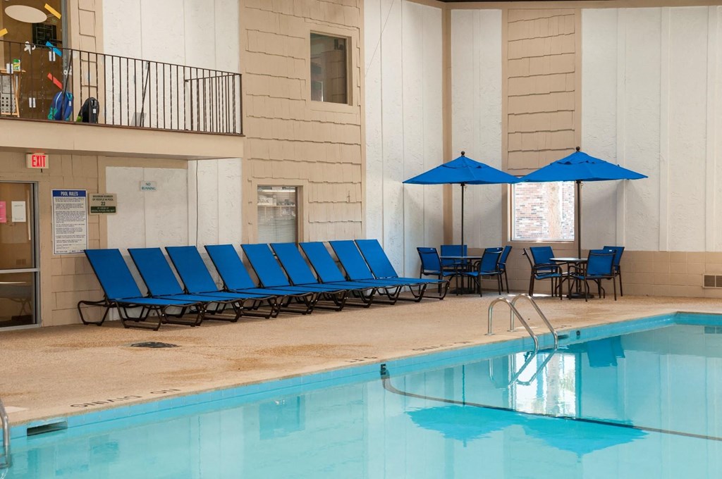 a swimming pool with blue chairs and umbrellas
