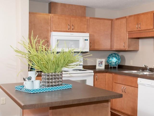 Carver Crossing Apartment Kitchen with Medium Wood Cabinetry and Large Center Island