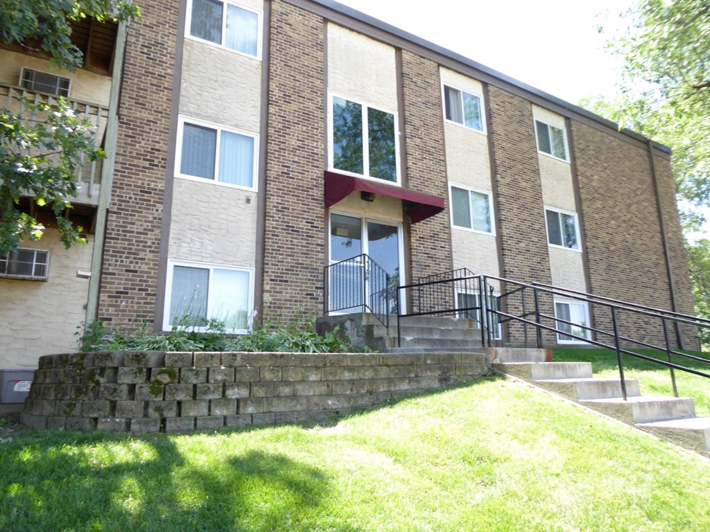 an apartment building with stairs and grass in front of it