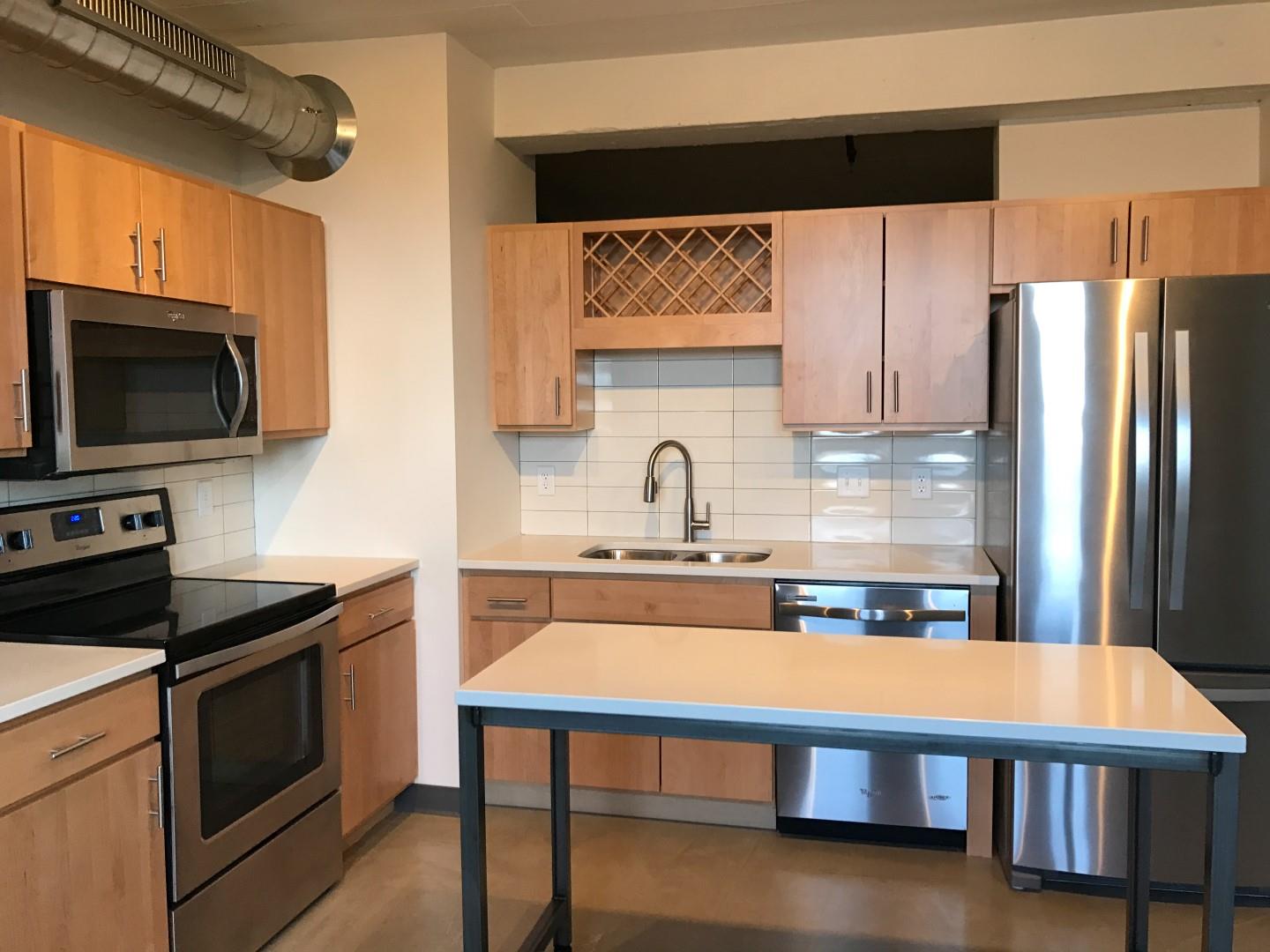 Open Kitchen with Wooden Cabinetry, Stainless Steal Appliances and White Counter Tops at Minneapolis Apartment