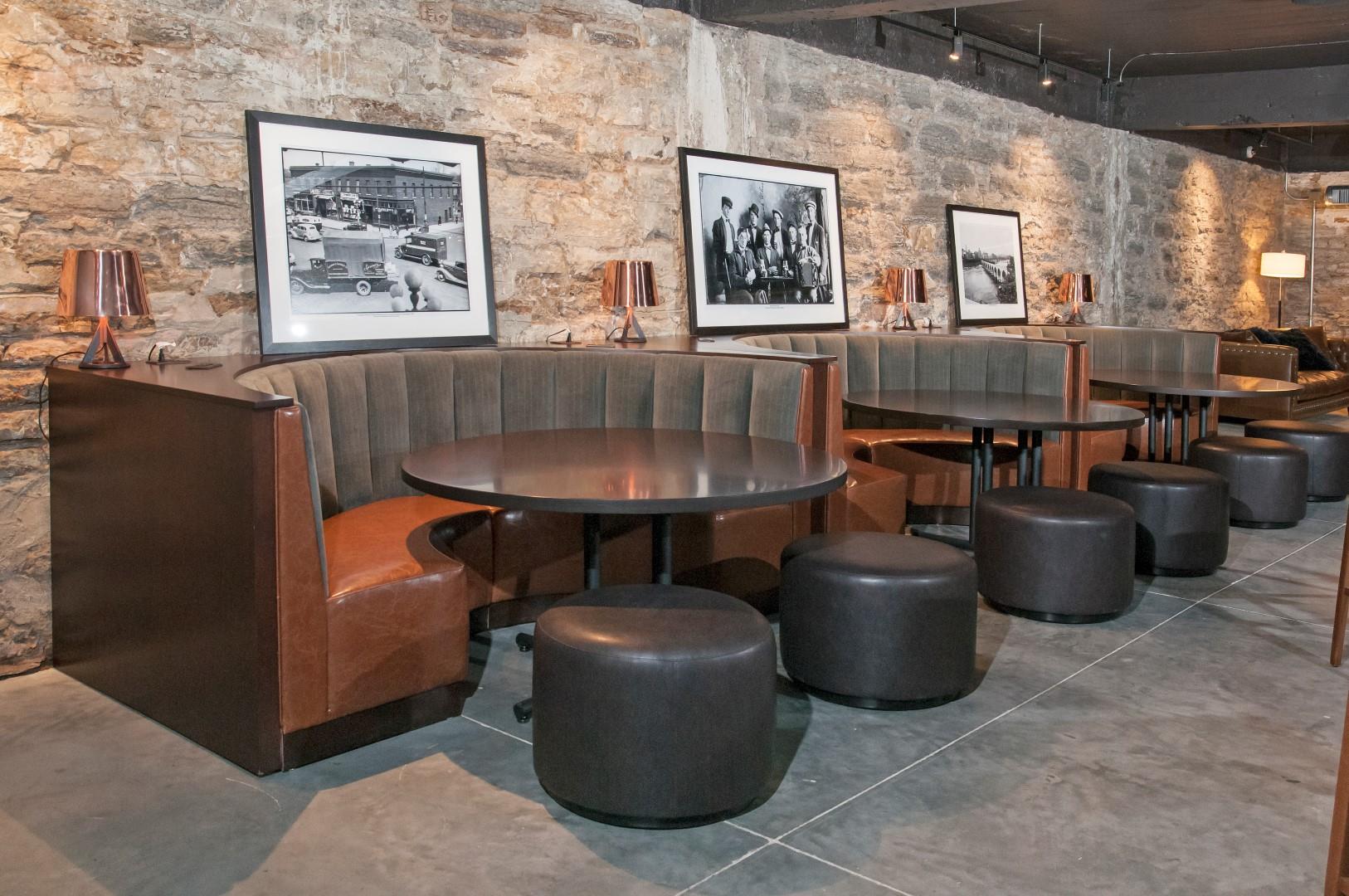 Club Room with Quarter-Circle Booths Around Circle Tables In Front of Exposed Brick Wall at 700 Central Apartments, MN, 55414